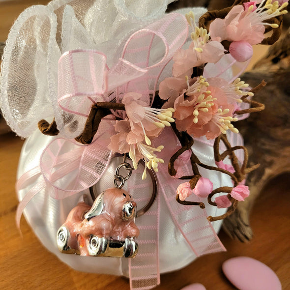Bomboniera bimba in raso bianco con fiori di pesco e portachiavi smaltato rosa